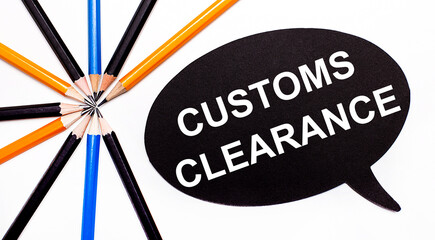 Wooden card with the text CUSTOMS CLEARANCE on a black background near multicolored pencils.