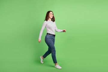 Full size profile side photo of young attractive girl walk empty space isolated over green color background © Tetiana