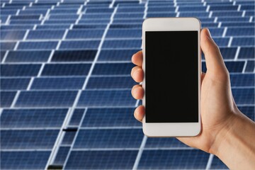 Man hand holding the telephone for monitoring performance in solar power plant, blank screen