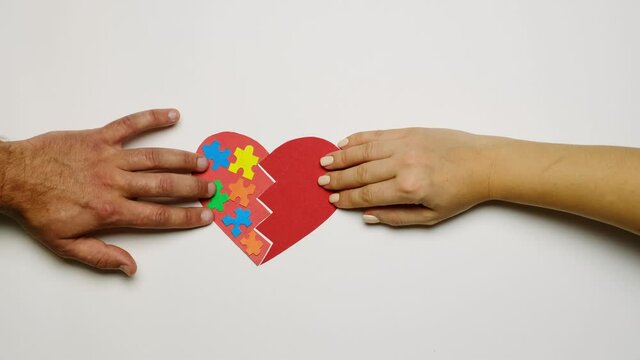 The couple reunites the two halves of the heart with the image of puzzles on one part. A symbol of support for people with autism syndrome. World Autism Awareness Day