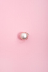 One decorative pink ball on a pink background. Top view, flat lay.