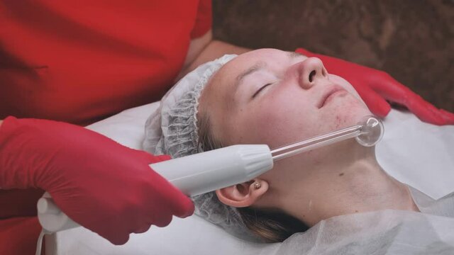 Darsonvalization of the face in a young girl with problem skin.