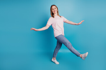 Fototapeta na wymiar Photo of positive carefree funny lady girlish walk concept wear white t-shirt isolated on blue background