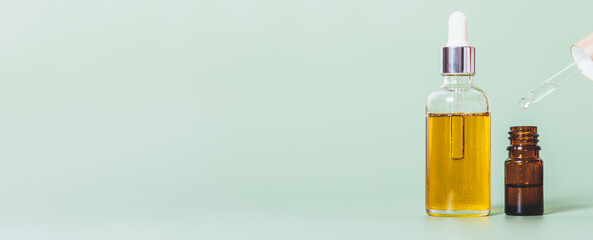 Essential oil bottles with dripping dropper on green background