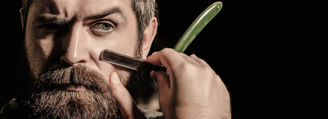 Vintage straight razor. Mens haircut. Man in barbershop. Handsome bearded hairdresser is holding a...