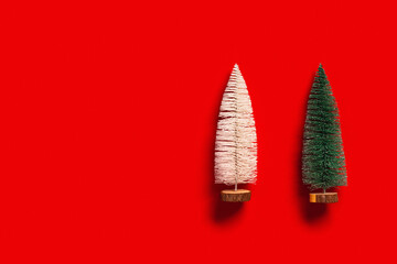 Christmas tree green and white colors on red background with copy space. Bright minimal New Year flat lay with plastic festive fir, holiday winter concept