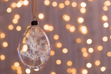 Hanging Christmas Glass bauble filled dried flowers, grass. Botanical Christmas ornaments with blurred bokeh background. Design transparent ball for New Year or xmas treey