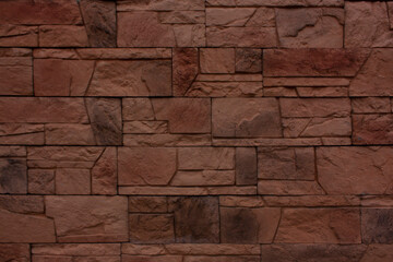 Dark red wall of old brick close-up. Brick texture made of uneven elements.
