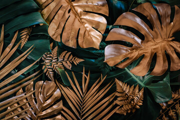 Creative nature background. Gold and green tropical Monstera and palm leaves. Minimal summer...