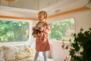 Little girl holds camera in motorhome, camping