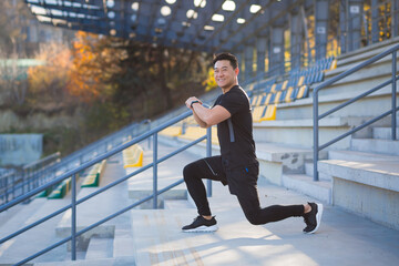 Male athlete trains in a backpack, asian fitness performs exercises outside the stadium in the...