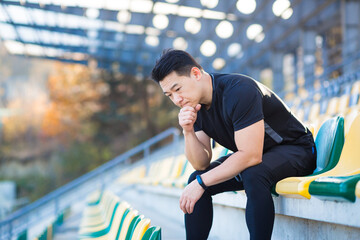 Frustrated Asian male athlete depressed, dissatisfied with the result of his training, in despair...