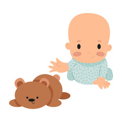 little boy in green pajamas reaches for a toy teddy bear toddler on a white background cute baby playing on the floor