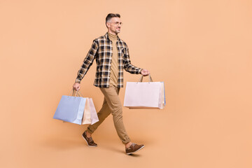 Full size profile side photo of mature man hold bag walk look empty space boutique isolated over...