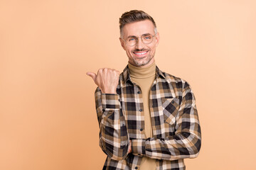 Fototapeta premium Photo of mature man indicate thumb empty space direct recommend advert isolated over beige color background
