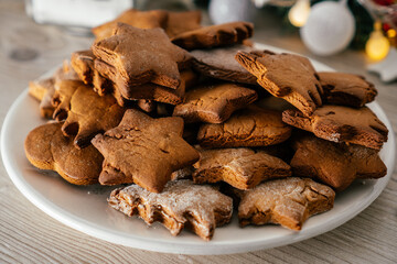 Partially blurred plate of gingerbread cookies in shape of christmas trees, stars and hearts on kitchen countertop
