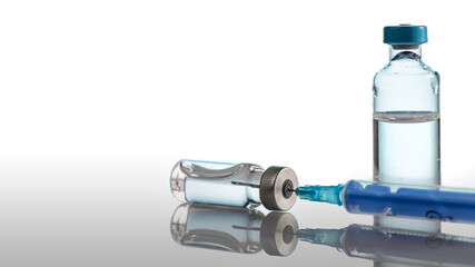 Two ampoules and syringe with the needle taking up the contents of the ampoule. Injection concept. 
