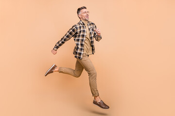 Fototapeta na wymiar Full body profile side photo of cheerful man run look empty space motion rush isolated over beige color background