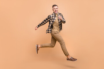 Fototapeta na wymiar Full size profile side photo of excited active man runner jump discount hurry isolated over beige color background
