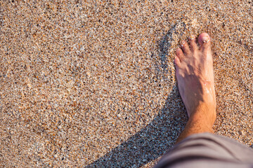 Men's bare feet stand on a sandy beach. Top view, flat lay