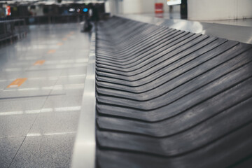 A baggage claim area in a hall of an airport arrival zone with a moving empty conveyor belt...
