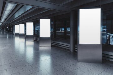 Five empty vertical posters mock-ups glowing with a LED neon light in an airport terminal; a group...