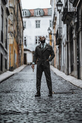 A fashionable mature bearded bald African-American man in dark-green elegant custom-made overalls...