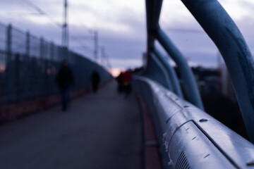 Unknown people in silhouette walking on steel bridge at twilight. Dark and suspense atmosphere...