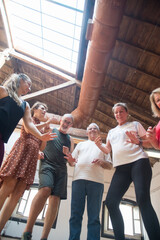 Positive senior dance group standing in semicircle in studio. Smiling pensioners having fun after...