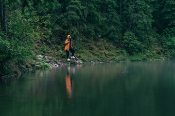 Fototapeta na wymiar woman hiker in yellow raincoat at lake beach