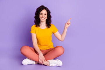 Full body photo of cheerful woman indicate finger empty space ad promo recommendation way isolated violet color background