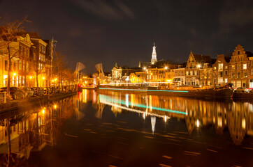 Fototapeta na wymiar Haarlem, The Netherlands, November 19, 2021: view along Spaarne river at night with a lighttrail of a boat that just passed an opened drawbridge