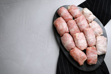 Uncooked stuffed cabbage rolls on grey table, top view. Space for text