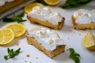 Lemon cake with protein cream, on a light background, with lemon slices and mint leaves.
