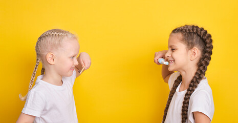 cheerful girls brush their teeth on a yellow background