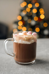 hot cocoa with marshmallows in a glass transparent cup on the background of a Christmas tree. cozy atmosphere. holiday