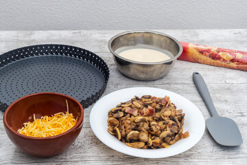 Ingredients for quiche, cheese, mushrooms and bacon on work table. Concept of home and traditional cooking