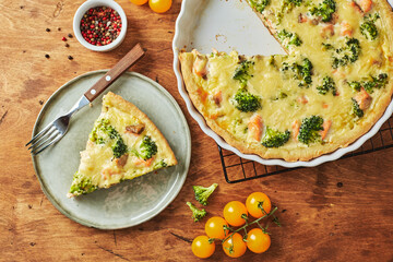 Homemade quiche with red fish, salmon, broccoli and cheese on wooden background