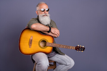Photo of mature brutal handsome man sit armchair stage guitar eyewear isolated over grey color...