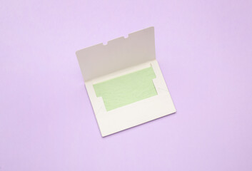 Facial oil blotting tissues on violet background, top view. Mattifying wipes