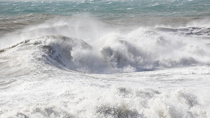 big waves breaking on the shore, with white foam
