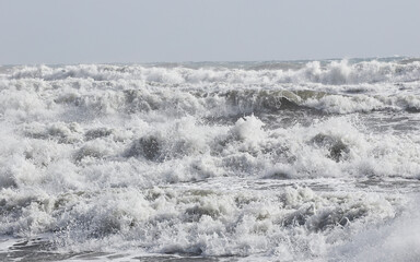 big waves breaking on the shore, with white foam
