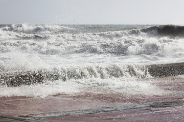 big waves breaking on the shore, with white foam