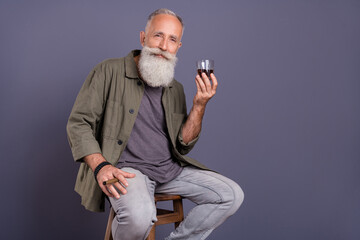 Photo of senior rich man drinking cognac sit restaurant free-time isolated over grey color background