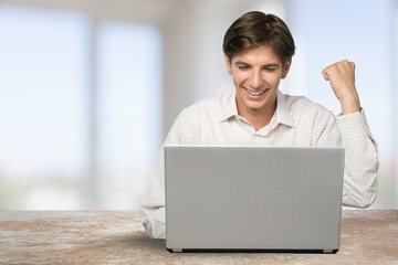 Excited man emotionally celebrating success using laptop in home office,