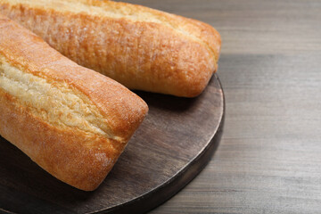 Tasty baguettes on wooden table, closeup. Space for text