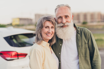 Photo of aged cheerful couple husband wife embrace enjoy vacation travel car transport driver city outdoors
