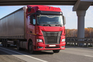Fototapeta na wymiar Big red truck moves under a bridge
