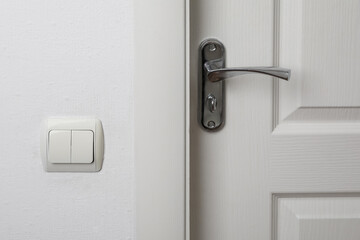 Modern light switch on white wall near door