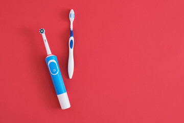 different toothbrushes on red background, electric toothbrush or plastic toothbrush,